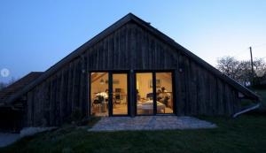 a large wooden house with glass doors in a field at Bauernhaus Pledlberg in Winzer