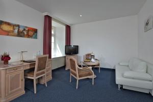 a living room filled with furniture and a tv at Hotel Stadt Hameln in Hameln