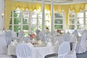 Zimmer mit weißen Tischen, Stühlen und Fenstern in der Unterkunft Hotel Stadt Hameln in Hameln