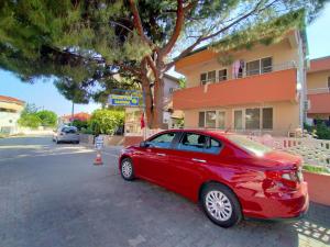 a red car parked on the side of a street at Berk Apart Hotel in Kucukkuyu