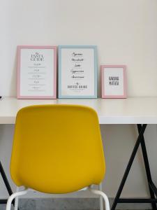 a yellow chair in front of a table with three pictures at AllYouCanTrip - La Nova in Naples
