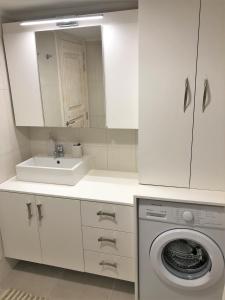 uma cozinha branca com um lavatório e uma máquina de lavar roupa em Stone House Halki em Halki