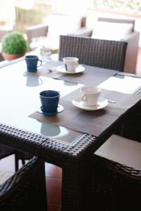 a table with three cups and saucers on it at B&B La Bouganville in Alghero