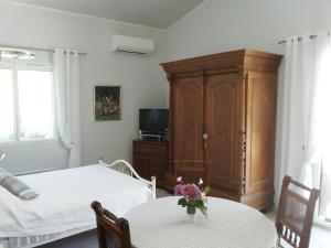 Laroque-des-AlbèresにあるLe Quatorzeのベッドルーム1室(ベッド1台、花のテーブル付)