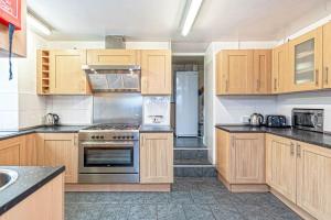 a kitchen with wooden cabinets and a stove top oven at The Trees in Amlwch