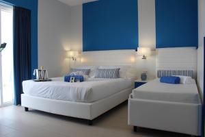 two white beds in a room with blue walls at Terrazze Naos in San Leone