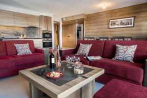 a living room with red couches and a table at CGH Résidences & Spas Alpaga in La Toussuire