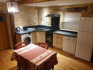 a kitchen with a table and a white refrigerator at Domaine du Bois Noir in Milhac