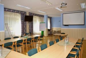 a conference room with tables and chairs and a screen at Brandiser Parkhotel in Brandis