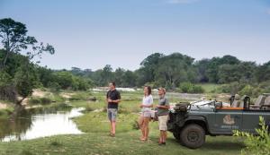 un gruppo di persone in piedi accanto a un veicolo militare di Leopard Hills Private Game Reserve a Riserva di Sabi Sand