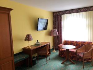 a hotel room with a couch and a desk and a table at Brandiser Parkhotel in Brandis