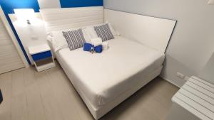 a small bedroom with a white bed and a night stand at Terrazze Naos in San Leone