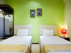 two beds in a room with a green wall at Eight Days Boutique Hotel - Mount Austin in Johor Bahru