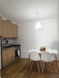 uma cozinha com uma mesa branca e cadeiras brancas em São Roque View Apartment em Aveiro
