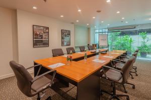 une salle de conférence avec une grande table et des chaises en bois dans l'établissement Oakwood Residence Sukhumvit 24 - SHA Extra Plus, à Bangkok