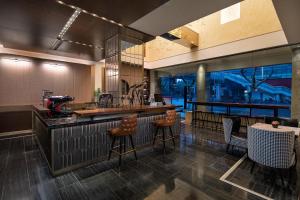a restaurant with a bar with stools and a table at Kasion Pugis Hotel in Yiwu