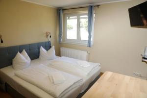 a white bed in a room with a window at Pension Elfmeter in Rheinsberg