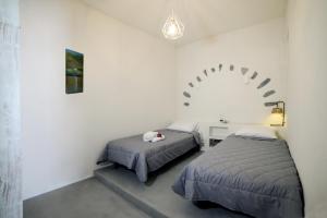 KorissiaにあるAmphoras Apartmentsの白い部屋にベッド2台が備わるベッドルーム1室