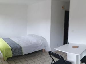 a bedroom with a bed and a chair and a table at coquelicot in Massiac