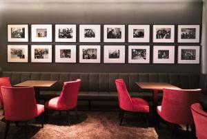 a restaurant with red chairs and tables and pictures on the wall at Romantik Hotel Kleber Post in Bad Saulgau