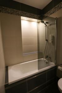 a bathroom with a tub and a shower with a mirror at Hotel Fryderyk in Nysa
