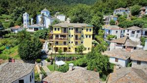 une grande maison jaune dans un village avec des maisons dans l'établissement Thassos Inn, à Panagia