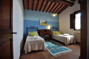 a bedroom with two beds and a table and a window at Linearis Holiday House in Poggibonsi