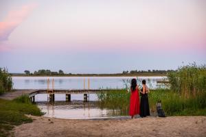 dos personas de pie en una playa cerca de un cuerpo de agua en Siedlisko Szymonka, en Ryn