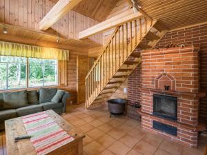 a living room with a brick fireplace and a staircase at Holiday Home Pihlajaniemi by Interhome in Sastamala