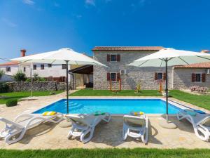 a villa with a swimming pool and two umbrellas at Holiday Home Bozac - ROJ417 by Interhome in Žminj