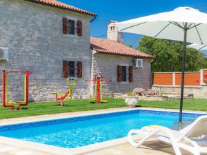 a house with a swimming pool and an umbrella at Holiday Home Bozac - ROJ417 by Interhome in Žminj