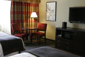 a room with a bed, chair, television and a lamp at The Hotel at Black Oak Casino Resort in Tuolumne