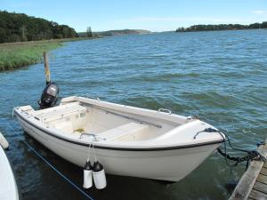 a white boat tied to a dock on the water at Chalet Norrkrog Utsikten by Interhome in Norrkrog