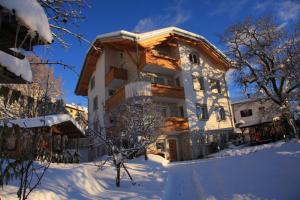 een huis met sneeuw op de grond ervoor bij Cortalta Mountain Lodge in Fai della Paganella