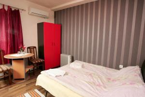 1 dormitorio con cama, mesa y armario rojo en Apartments Agape, en Belgrado