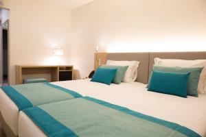 a bedroom with a large bed with blue pillows at Mafra Hotel in Mafra