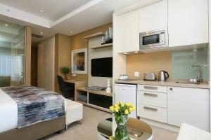 1 dormitorio con 1 cama y cocina con escritorio en 305 Sandton Skye, en Johannesburgo