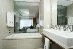 ein weißes Badezimmer mit einer Badewanne und einem Waschbecken in der Unterkunft 305 Sandton Skye in Johannesburg