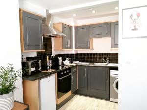 a kitchen with gray cabinets and a dishwasher at Eastside View Apartment in Whitby