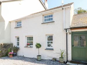 een wit huis met een groene deur en potplanten bij Garden Cottage in Haverfordwest