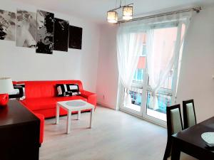 斯維諾烏伊希切的住宿－Apartament Baltis Świnoujście，客厅设有红色的沙发和大窗户