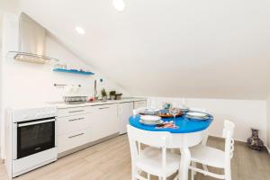 a white kitchen with a blue table and chairs at Casa Maria 2 in Mali Lošinj
