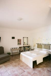een slaapkamer met een groot wit bed en een bank bij Ammon Garden Hotel in Pefkochori