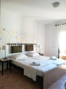 1 dormitorio con 1 cama grande con sábanas blancas en Ammon Garden Hotel, en Pefkohori