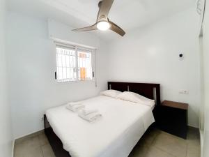 um quarto com uma cama branca e uma ventoinha de tecto em Best House Paola em Torrevieja