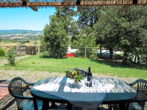 a table with a bottle of wine and flowers on it at Apartment Le Colmate-1 by Interhome in Montecatini Val di Cecina
