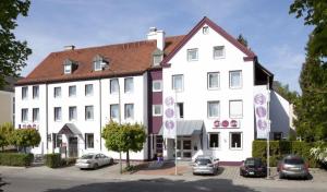 un gran edificio blanco con coches estacionados frente a él en Arthotel ANA Style Augsburg, en Augsburg