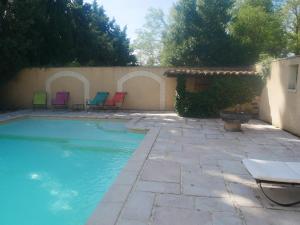 a swimming pool with chairs in a backyard at La Fénière in Vénéjan