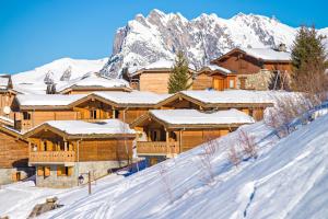 a lodge in the snow with mountains in the background at travelski home select - Chalets Le Grand Panorama II 3 stars in Valmeinier