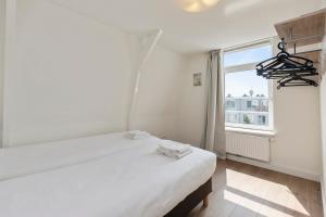 a white bedroom with a bed and a window at Central top floor apartment with private balcony - Apt 3 in Amsterdam